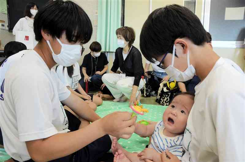 赤ちゃんを抱っこしてあやす生徒たち＝17日、熊本市北区