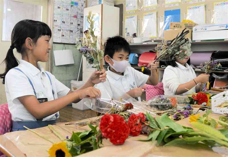 ドライフラワーや生花を使って壁飾りを作る一新小の3年生＝19日、熊本市中央区