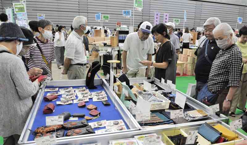 九州矯正展で受刑者が作った革製品などを品定めする来場者ら＝21日、益城町