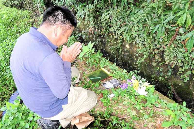 伯父が墜落したと思われる場所の近くで手を合わせる岩﨑昌弘さん＝9月21日、菊池市