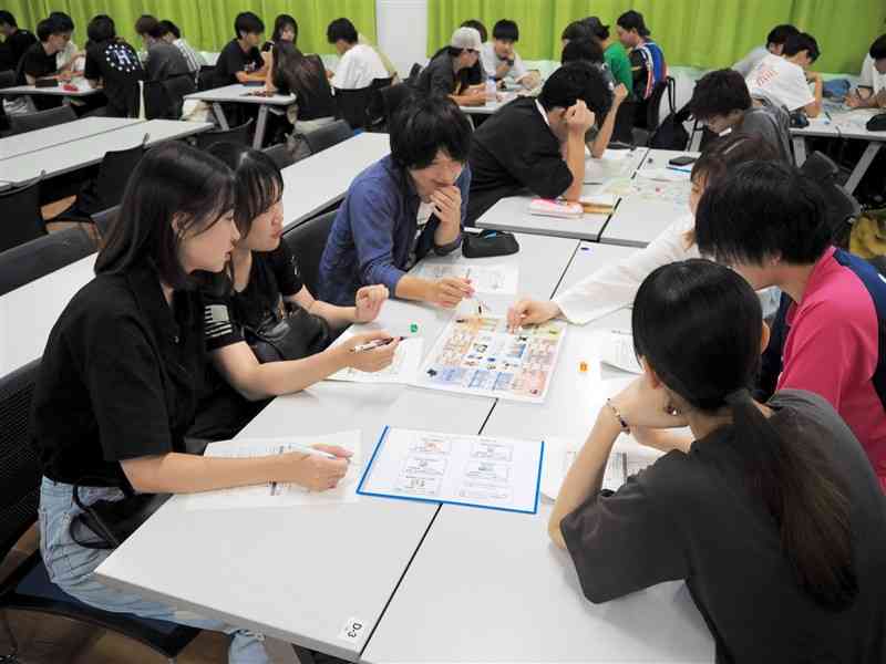 ボードゲームを通じて会社経営を学ぶ熊本学園大の学生＝20日、熊本市中央区