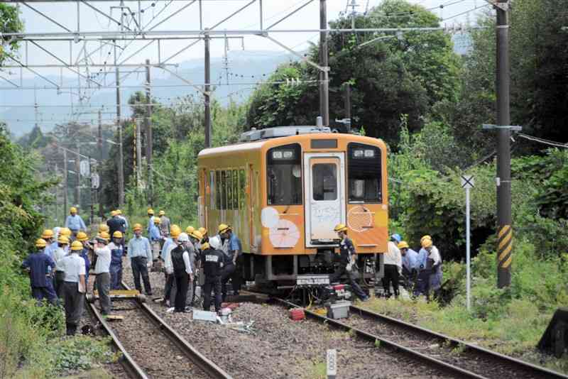 脱線した列車をジャッキアップしてレールに戻す肥薩おれんじ鉄道の社員ら＝25日、鹿児島県出水市