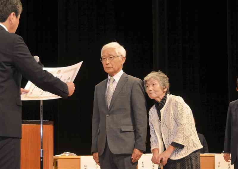 梅野智博熊日事業本部長（左）から表彰を受ける藤田雄美さん、亞紀子さん夫妻＝26日、宇城市