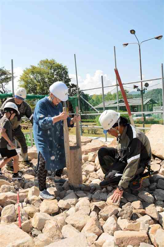 「たこ」を使ってぐり石を詰める参加者（中央）＝29日、人吉市