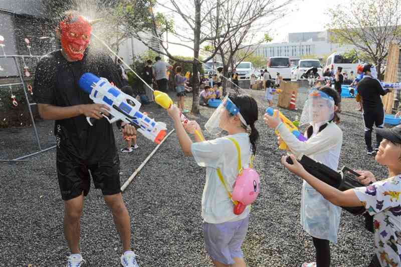 鬼役を水鉄砲で狙う子どもたち＝9月28日、菊陽町