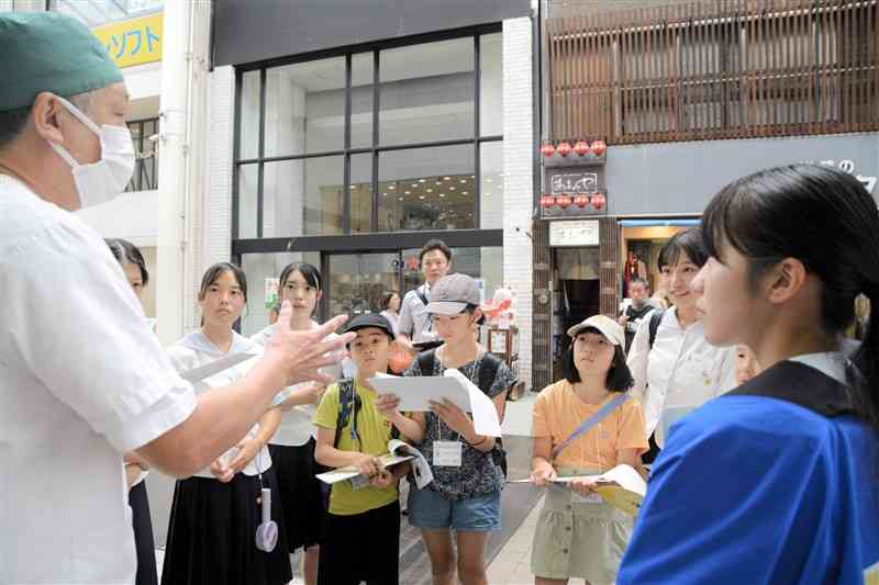 尚絅高生の案内で訪れた蜂楽饅頭で、材料などの説明を受ける小学生たち＝9月28日、熊本市中央区