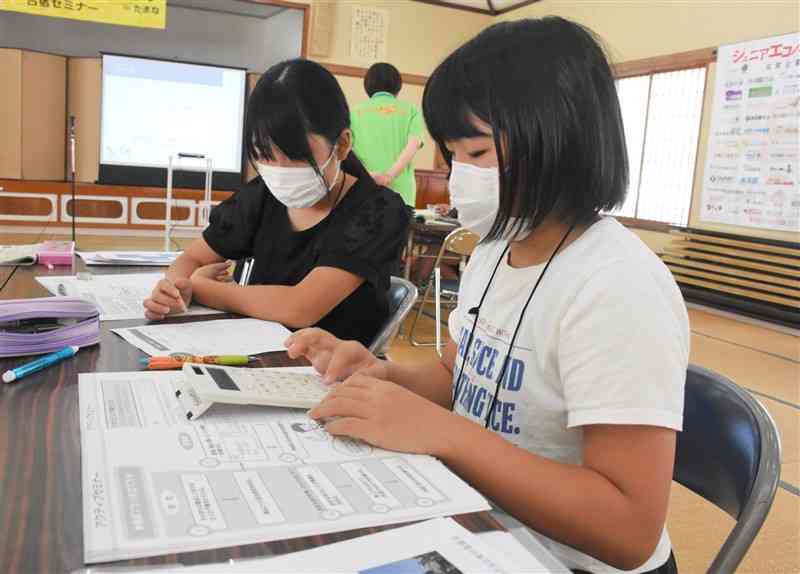 電卓を使って食材の仕入れ値を計算する児童＝9月28日、玉名市