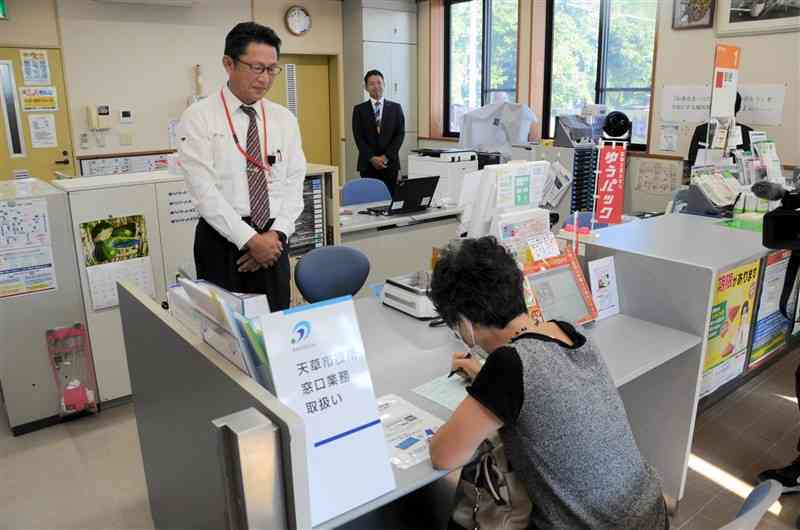 証明書発行のデモンストレーションで、申請を受け付ける郵便局職員（左）＝1日、天草市