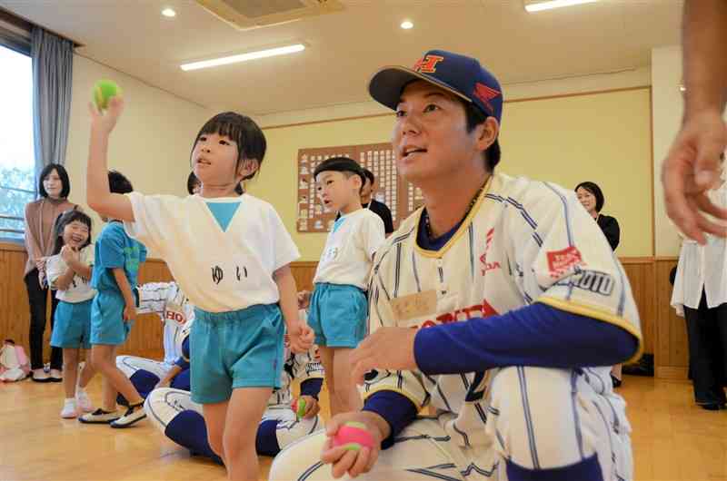 ボールを投げる園児と、ホンダ熊本硬式野球部の選手＝2日、熊本市東区