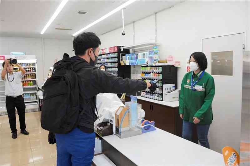 強盗訓練で店員にナイフのようなものを突きつける犯人役＝2日、芦北町