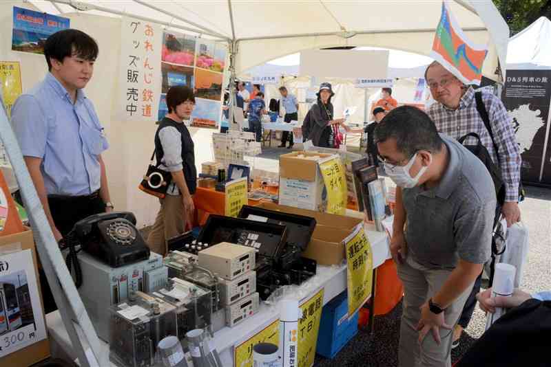 通信機器や時刻表などの鉄道部品を品定めする来場者＝5日、熊本市西区