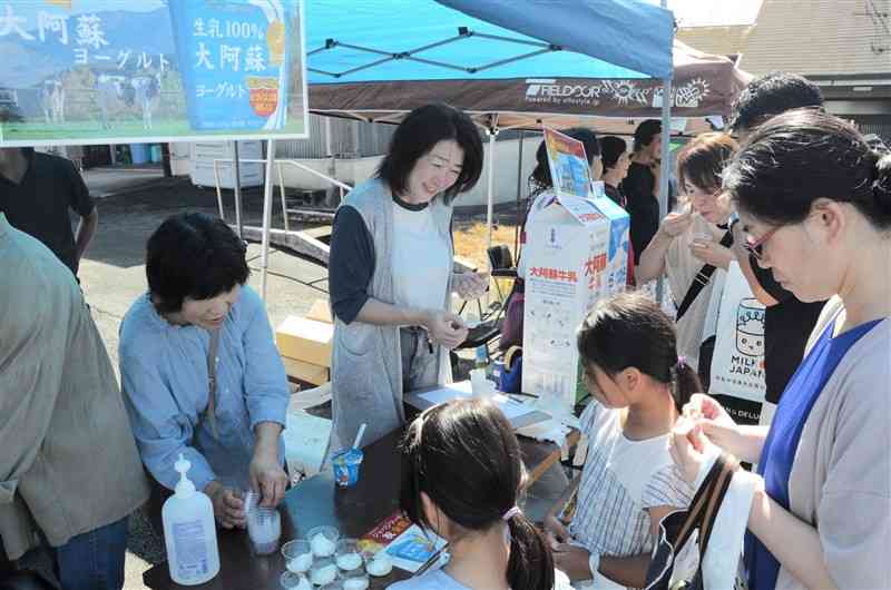 家族連れに牛乳やヨーグルトを勧めるJA熊本市酪農部会のメンバーら＝5日、熊本市東区