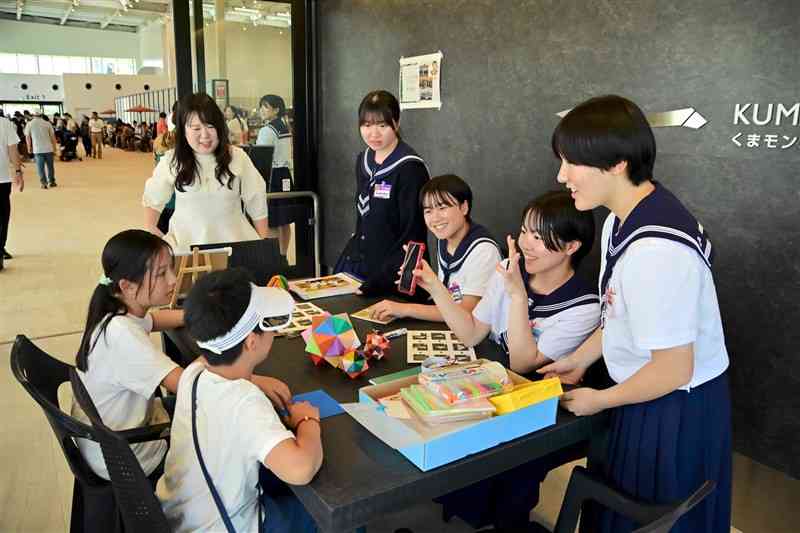 クルーズ客に折り紙を教える八代白百合学園高の生徒たち＝5日、八代市