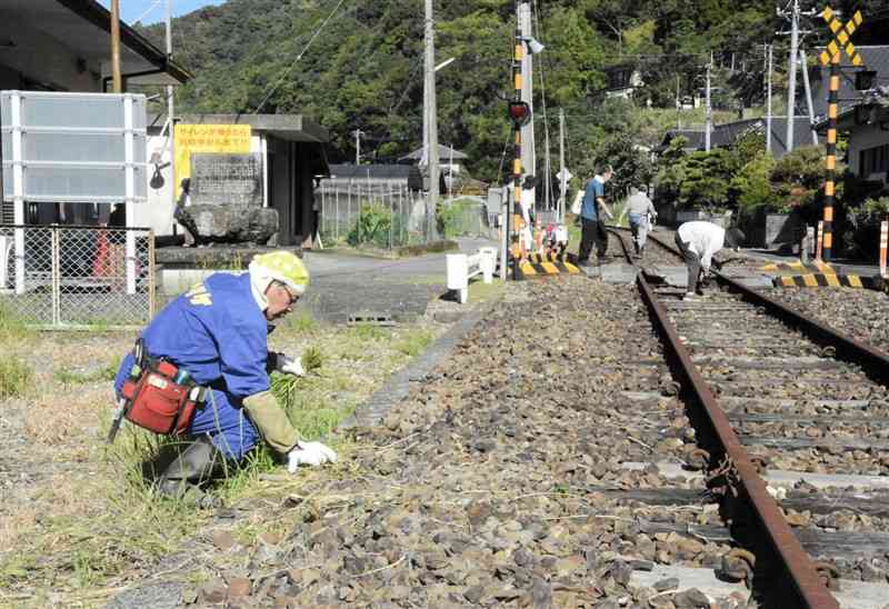 2020年7月の豪雨で被災し、不通が続くJR肥薩線で除草する沿線の住民ら＝6日、八代市