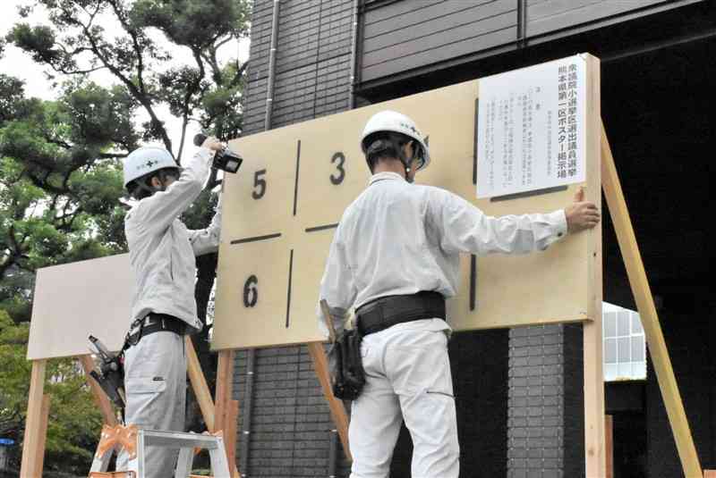 衆院選を前に立候補者のポスター掲示板を設置する作業員ら＝7日、熊本市中央区