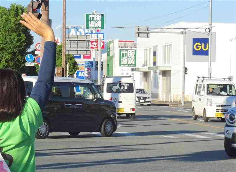 通勤時間帯に交差点で手を挙げる陣営関係者＝9日、菊陽町