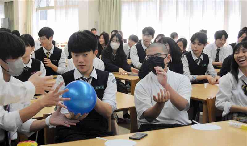 ボールを手渡す速さを競う開新高と朝日高の生徒ら＝9日、熊本市中央区