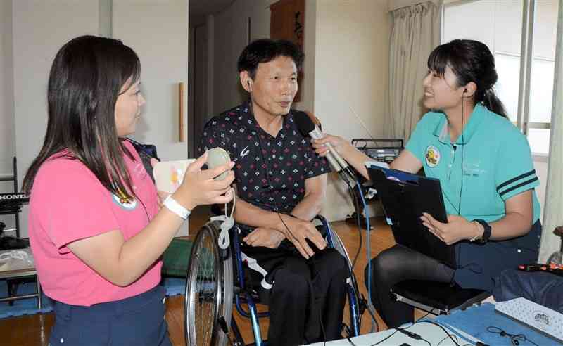 生中継で山本行文さん（中央）にインタビューする小出馨子さん（右）とタイムキーパーをする古戝沙季さん＝9月23日、熊本市北区