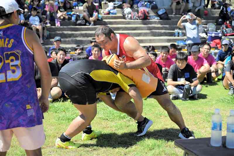 中学生のタックルを受ける垣永真之介選手（右）＝9月14日、荒尾市