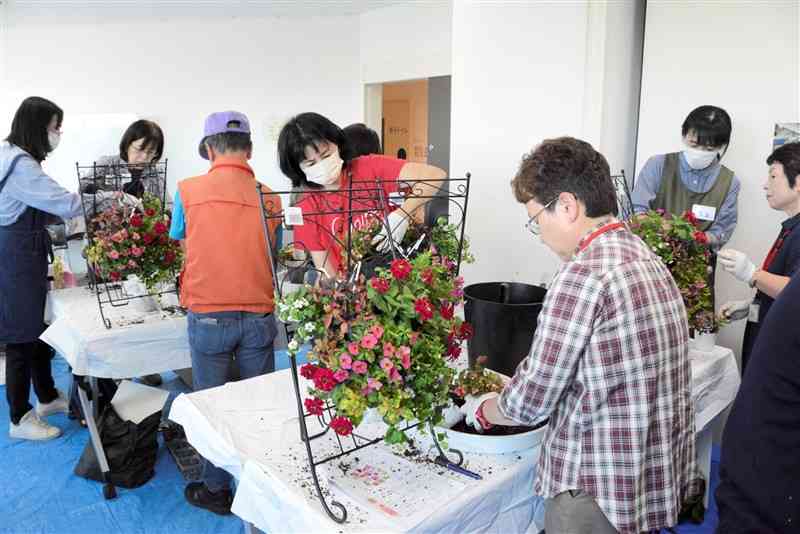 「くまもと花博」の開幕を控え、会場に飾る花鉢を制作する市民ボランティア「緑のマイスター」ら＝12日、熊本市中央区