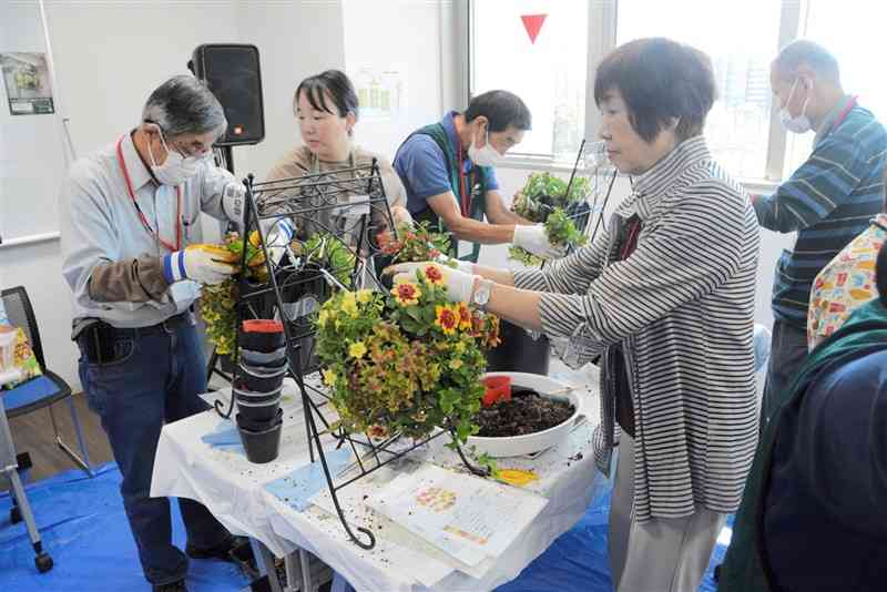 「くまもと花博」の開幕を控え、会場に飾る花鉢を制作する市民ボランティア「緑のマイスター」ら＝12日、熊本市中央区