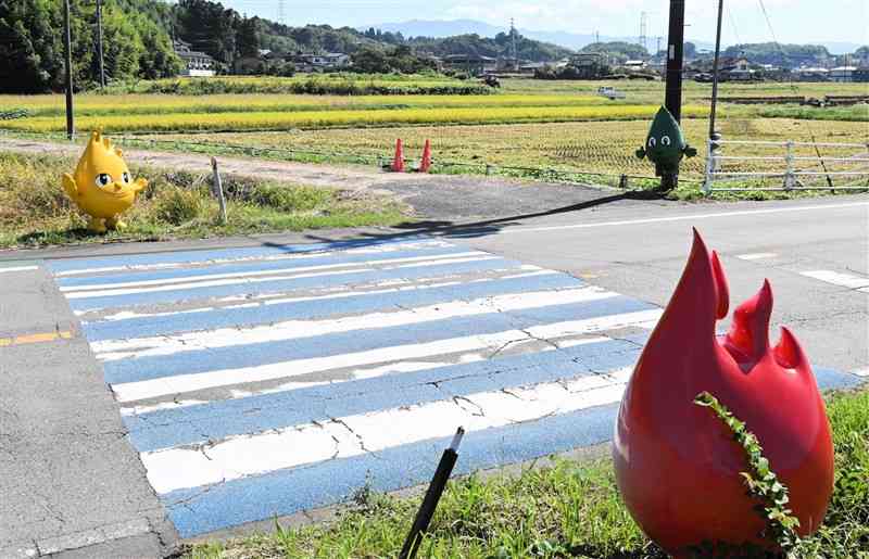 人吉市の広域農道の横断歩道で通行人らを見守る「ひのっこ」＝13日、同市