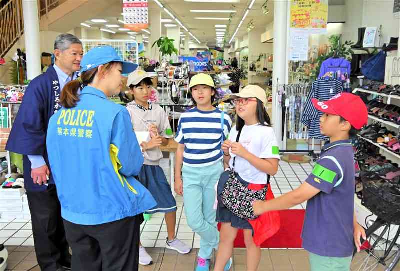 不審者に遭遇し、店舗に駆け込んで店員と警察官に事情を話す児童＝14日、八代市