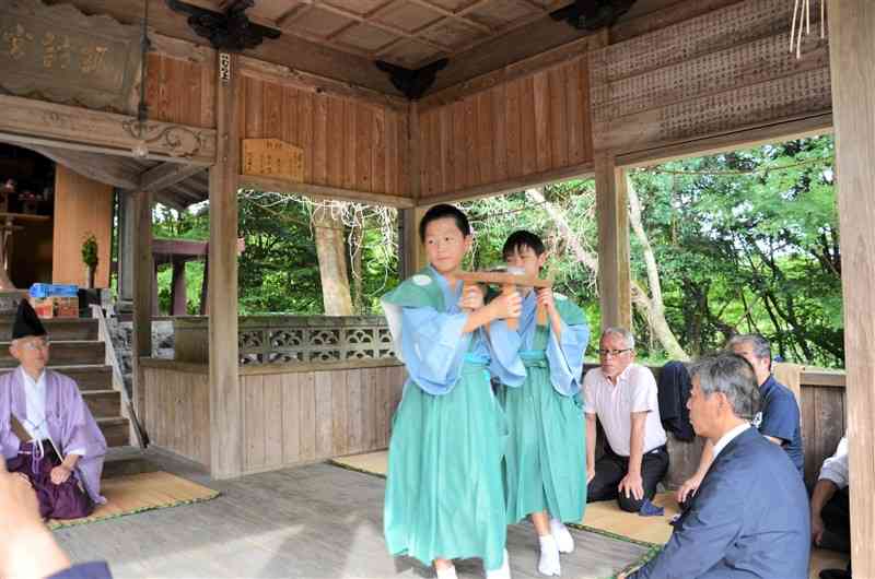 カレイを担いで上江田諏訪神社の拝殿内を回る松田虎琉さん（左）と荒木亮太さん＝15日、和水町