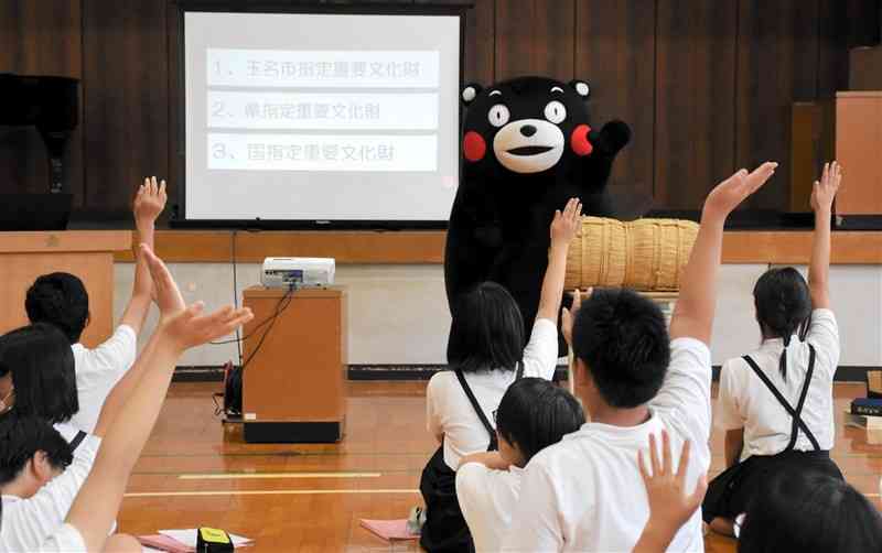 くまモンが出題したクイズに手を上げて答える児童たち＝17日、玉名市