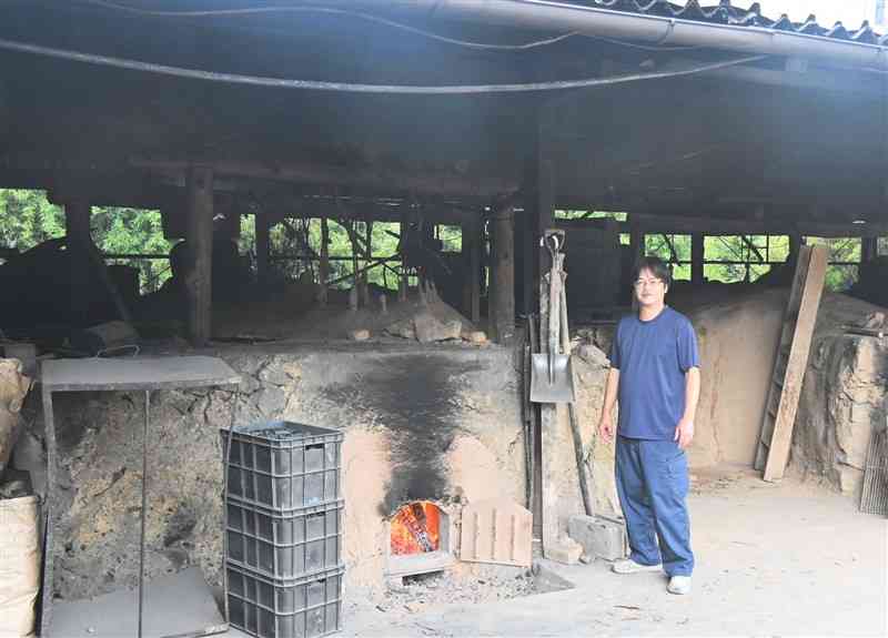 工場内の炭窯を案内する尾鷹林業の野村友彦社長＝17日、あさぎり町