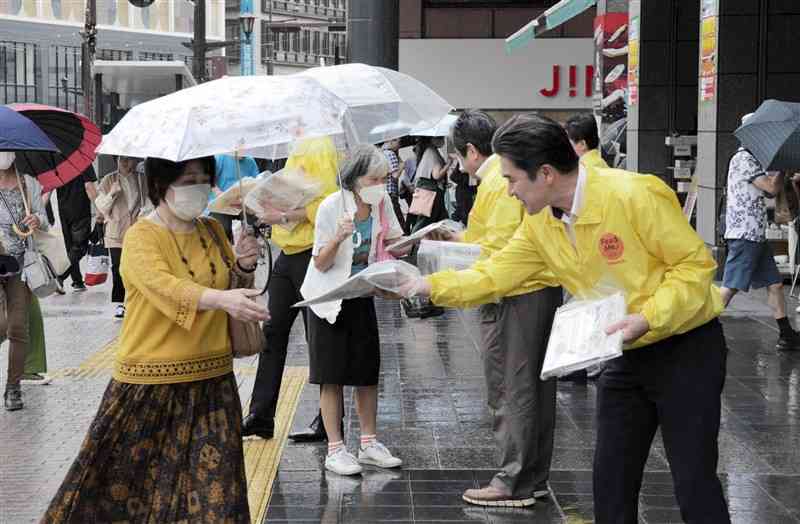 熊本県支部新聞公正取引協議会のメンバー（右）から新聞を受け取る買い物客ら＝19日、熊本市中央区