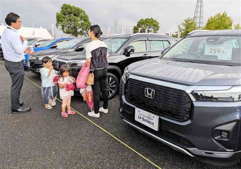 新車ディーラーが展示・販売している中古車を見学する家族連れ＝19日、益城町