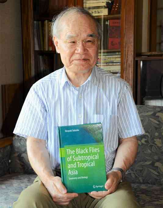 ブユ研究の成果をまとめた学術書を手にする高岡宏行さん＝9月、菊池市