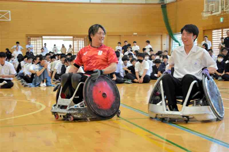 競技用車いすの体験で、生徒に話しかける島川慎一選手（左）＝21日、長洲町