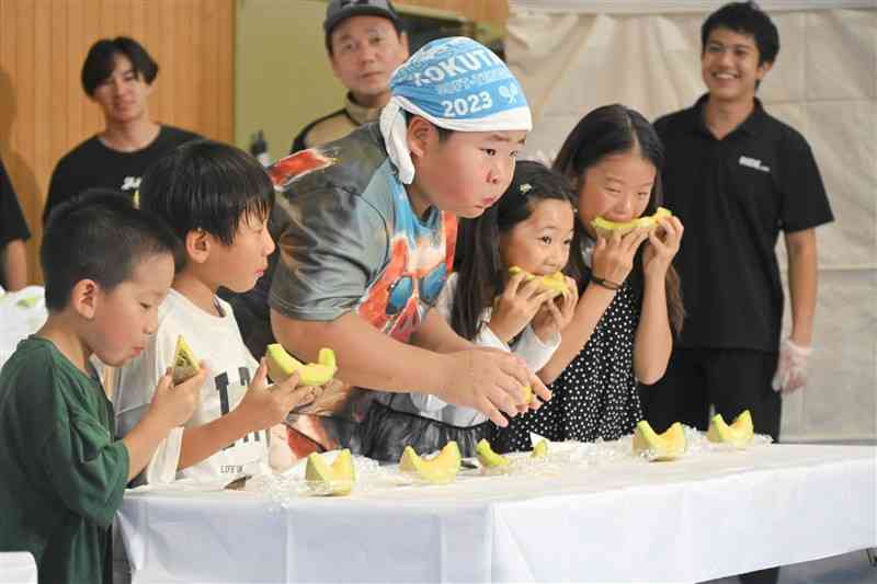 メロンの早食い大会に挑む子どもたち＝19日、菊池市