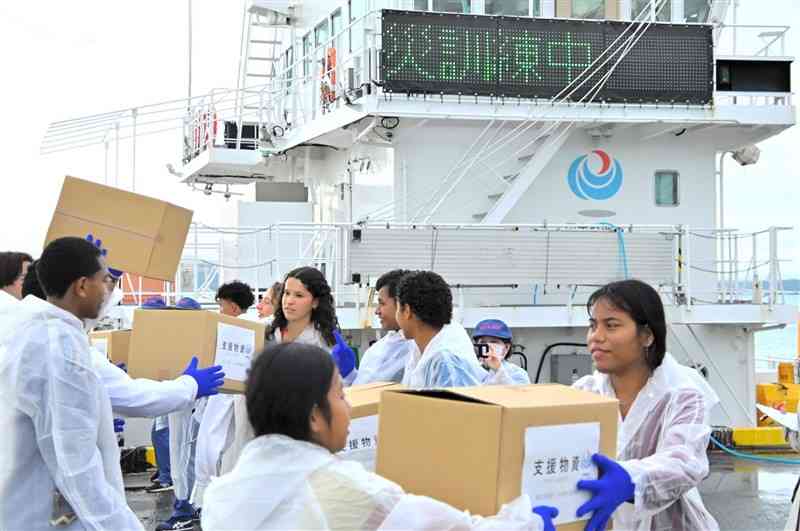 八代港であった防災訓練で、船から支援物資を下ろす作業を体験する各国からの参加者＝22日、八代市