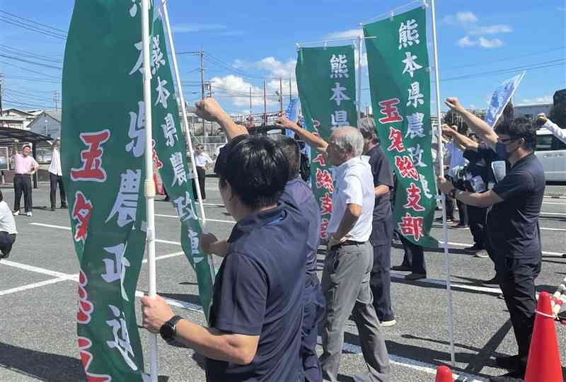 自民党候補の街頭演説で、県農政連ののぼりを持って気勢を上げる農家ら＝18日、玉名市