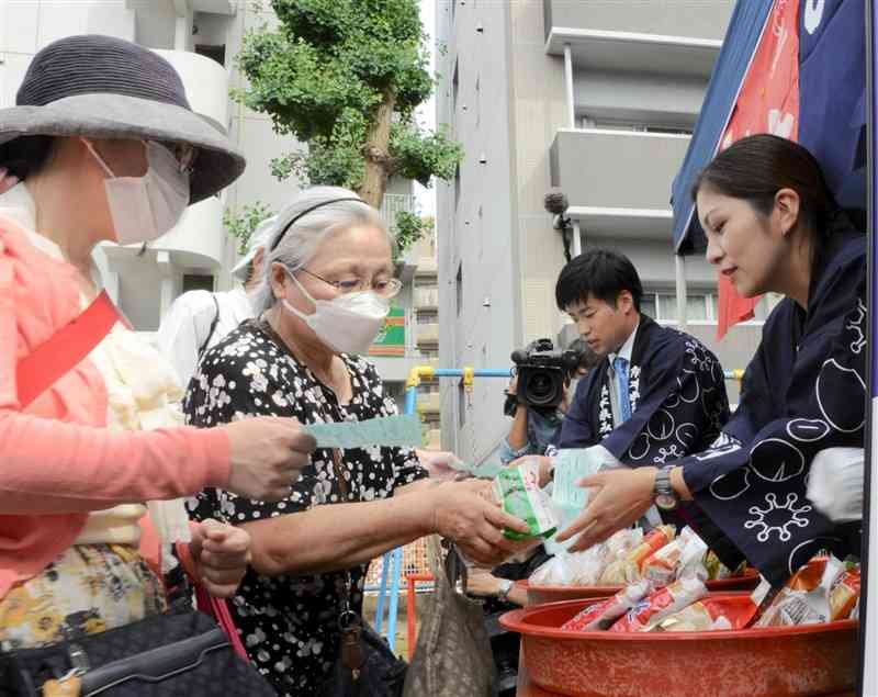 熊本県みそ醬油工業協同組合のメンバー（右）から、みそを受けとる参拝客＝25日、熊本市中央区