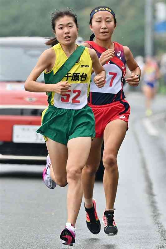 女子1区。第1中継所の300メートル付近で千原台の吉原（左）がルーテルのエース古木を抜き、トップに躍り出る＝熊本市東区（上杉勇太）