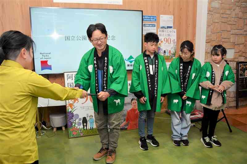 来場者200万人達成の証明書を受け取る男性（左から2番目）＝10月26日、阿蘇市