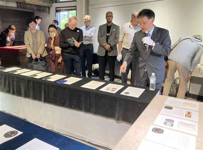 展示会で、所有する肥後鐔を紹介するニック中村会長（手前右）＝26日、熊本市西区