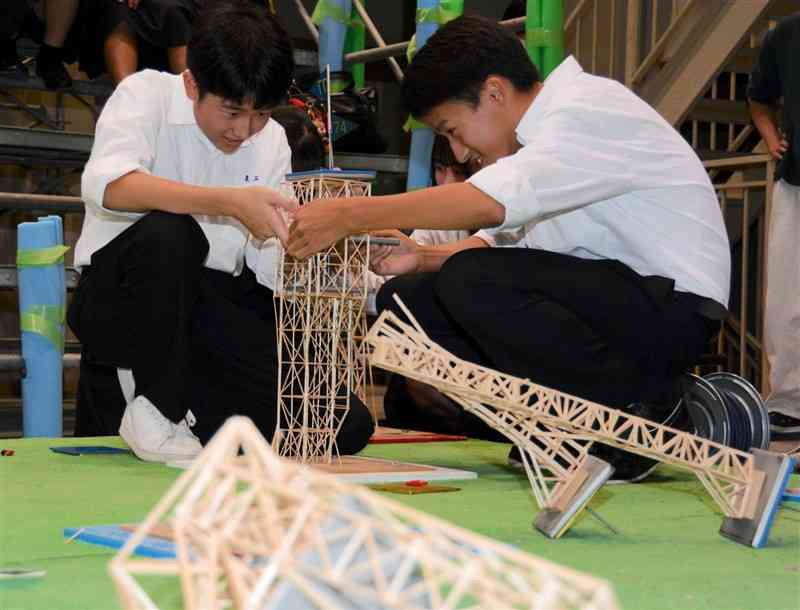 つまようじで作ったタワーに重りを載せる熊本工業高の生徒ら＝26日、熊本市西区