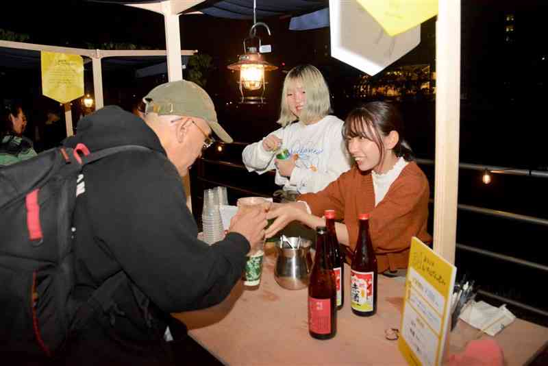 白川夜市で日本酒などを提供する崇城大の学生＝10月26日、熊本市中央区