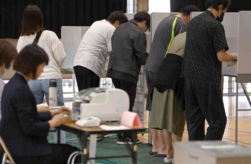 衆院選の投票所で、投票用紙に候補者名や政党名などを書き込む有権者＝27日午前、熊本市南区の力合小（小野宏明）