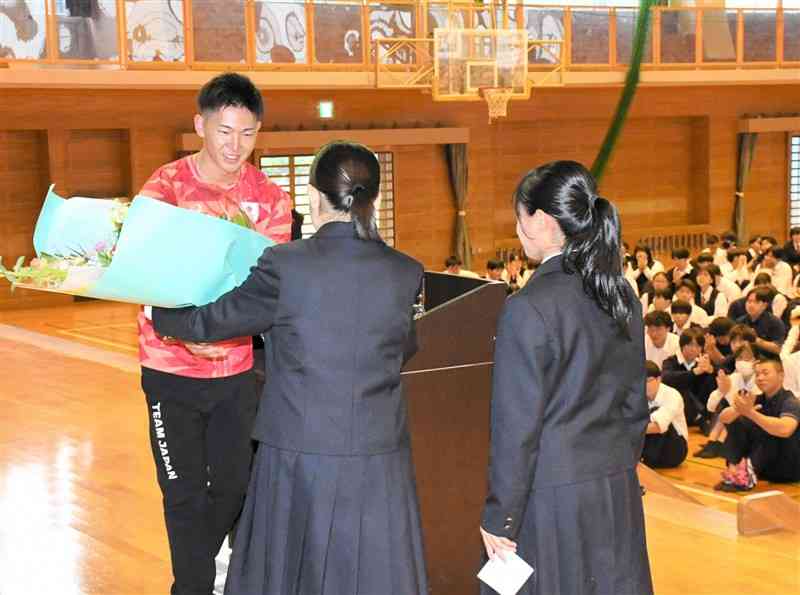 パリ五輪の出場報告会で、在校生から花束を贈られる筒江海斗（左）＝熊本市西区