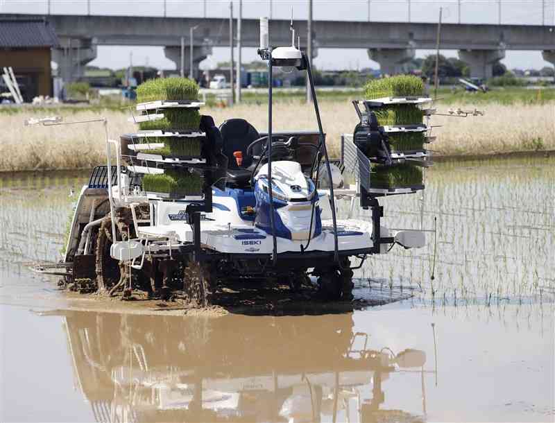 誰も乗せずに水田を進むロボット田植え機＝6月、茨城県つくばみらい市