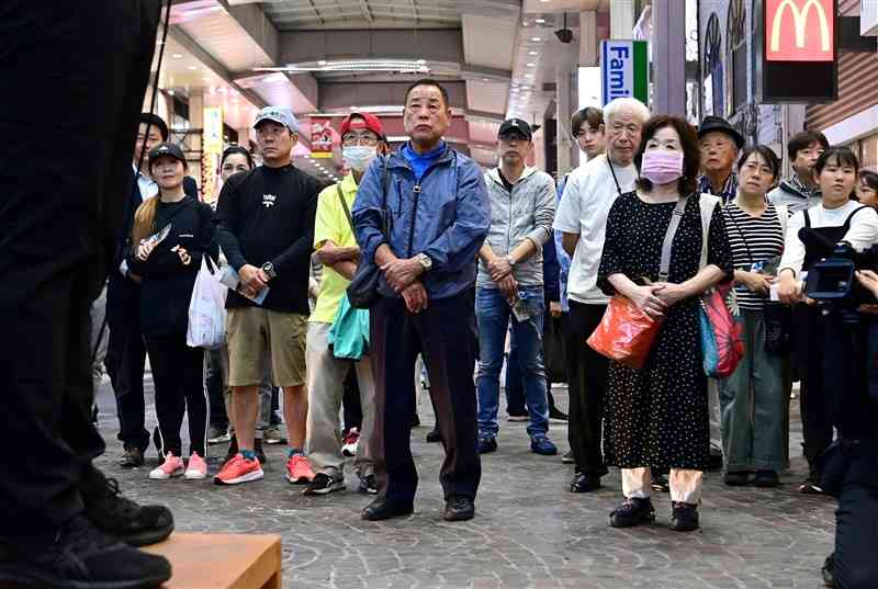 街頭演説で候補者（左）の訴えを聞く支持者ら＝10月26日、熊本市（谷川剛）