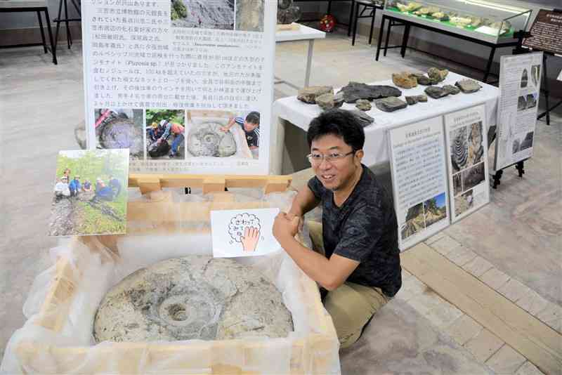 大型のアンモナイトの化石標本と小松俊文教授＝熊本市中央区