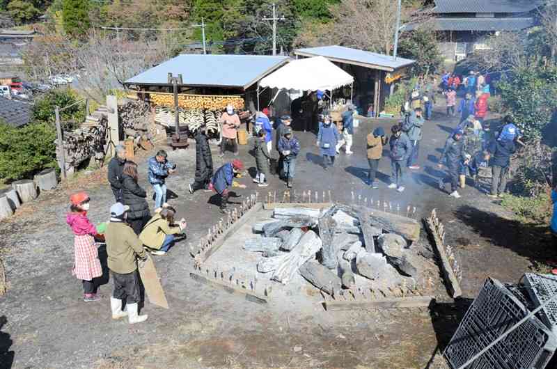 巨大なおき火の周辺に、ヤマメやイモなどを並べて焼き上げる高森田楽＝昨年11月、高森町