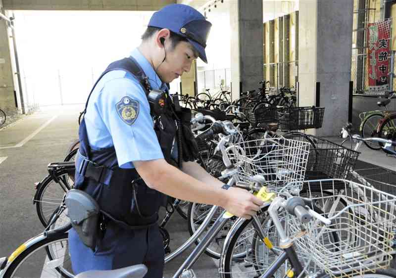 JR熊本駅の駐輪場で、自転車の施錠徹底を呼びかけるタグを付ける熊本南署員＝10月11日、熊本市西区